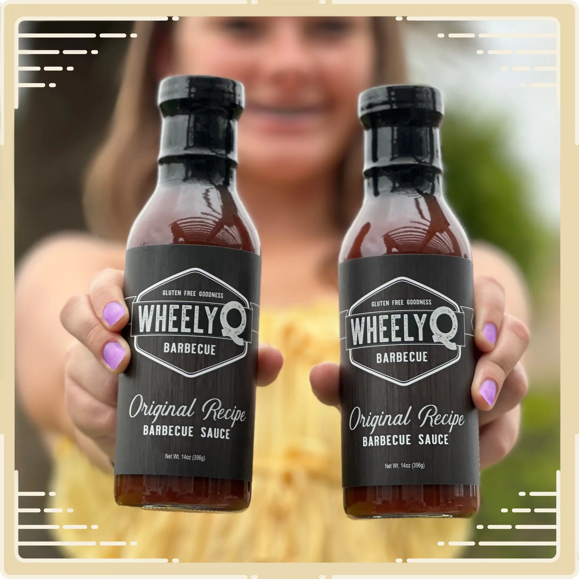 Image of two bottles of WheelyQ Barbecue Sauce being held by a beautiful girl that is faded in the background.