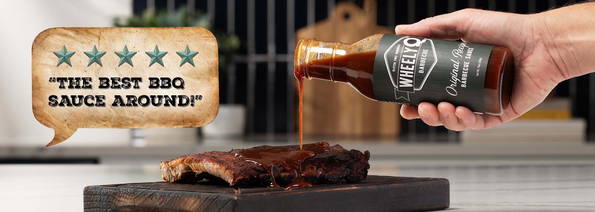 Bottle of WheelyQ Barbecue Original Recipe Barbecue Sauce being poured over ribs with a speech bubble praising it as 'The Best BBQ Sauce Around'.
