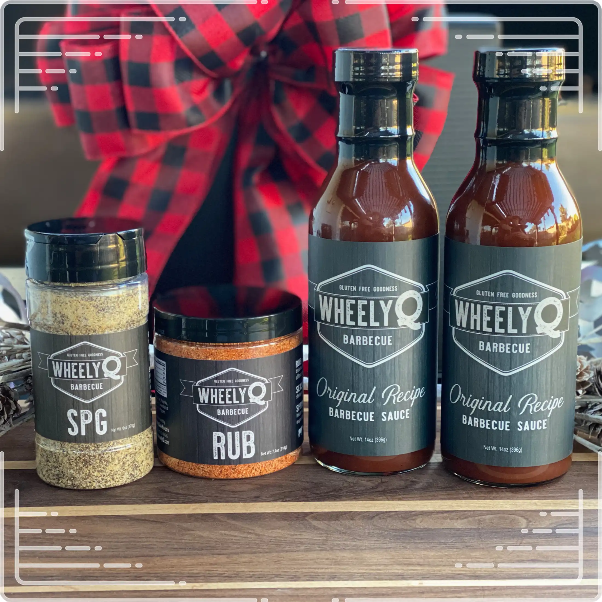 An image of a Barbecue Gift Box sold by WheelyQ Barbecue.  The gift set include 2 bottles of Barbecue Sauce, 1 bottle of SPG Seasoning and 1 jar of All-Purpose Rub or Ancho Espresso Seasoning.