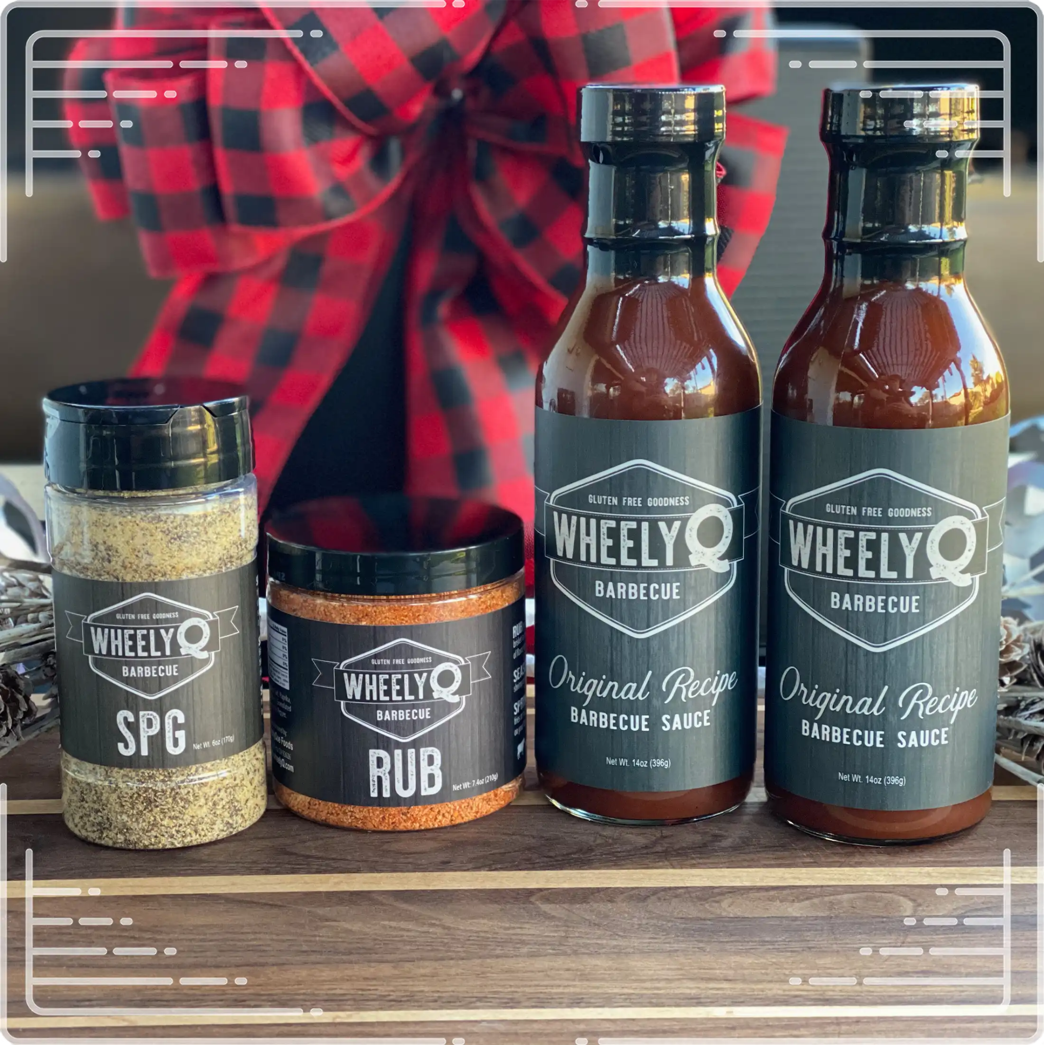 An image of a Barbecue Gift Box sold by WheelyQ Barbecue.  The gift set include 2 bottles of Barbecue Sauce, 1 bottle of SPG Seasoning and 1 jar of All-Purpose Rub or Ancho Espresso Seasoning.