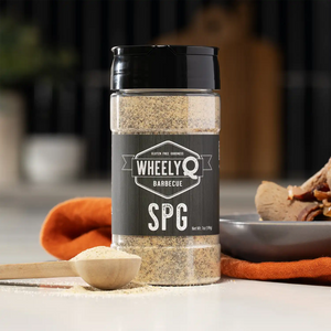 A bottle of WheelyQ SPG Seasoning (Salt, Pepper, Garlic) with a spoonful of spice on a kitchen counter.